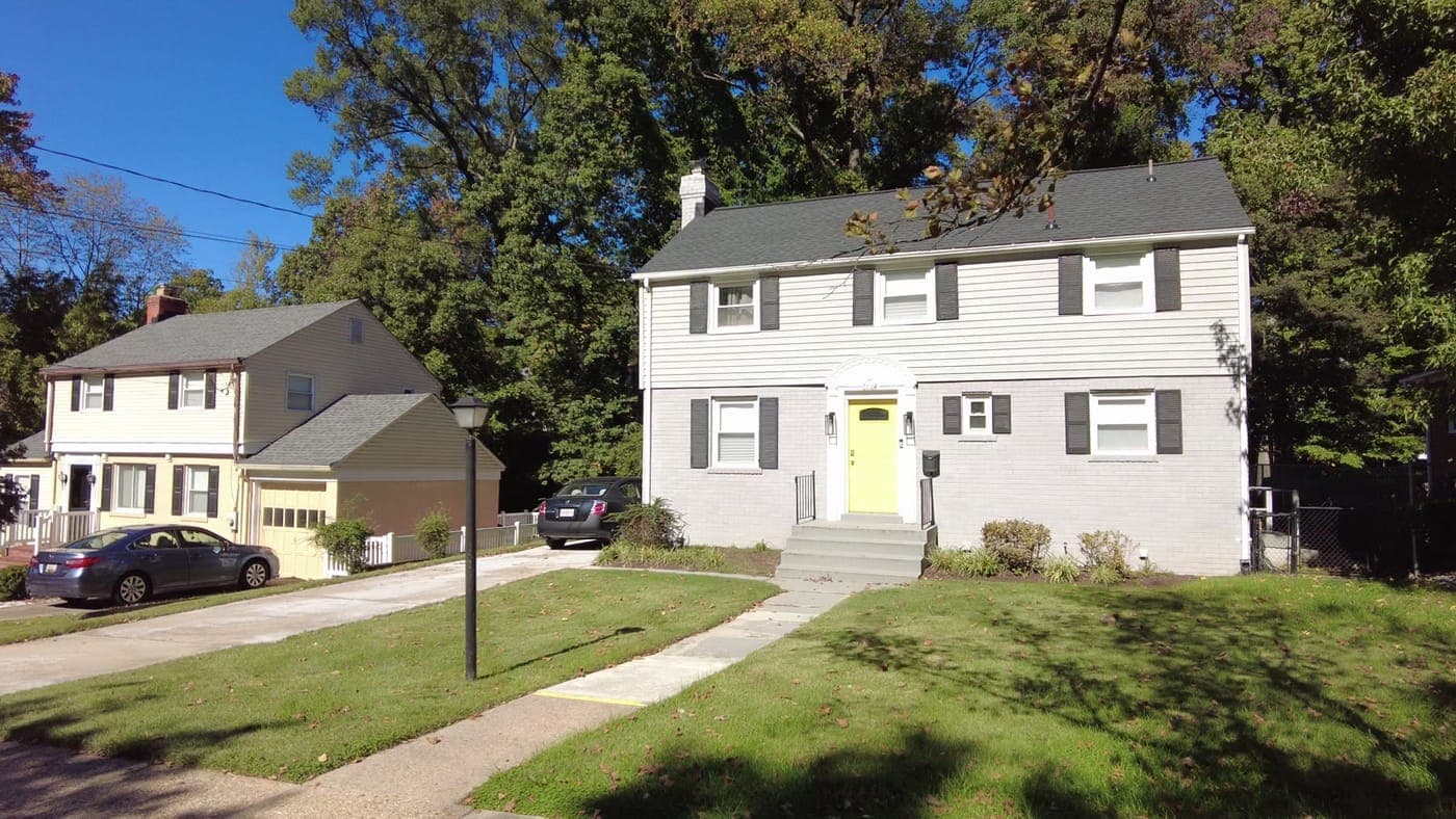 A white brick colonial with a yellow front door on a Cheverly street